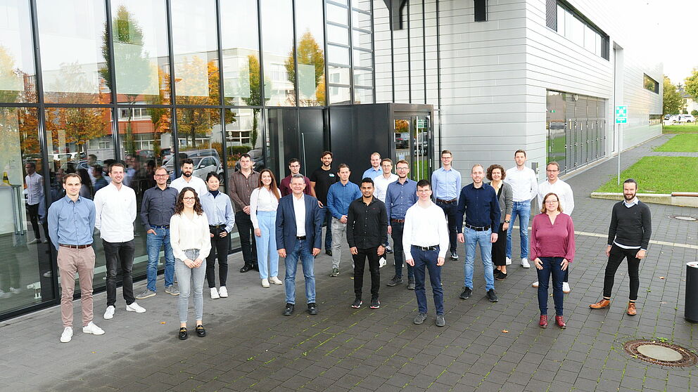 Mitarbeitende des Lehrstuhls für Leichtbau im Automobil stehen vor dem Y-Gebäude auf dem Campus der Uni Paderborn