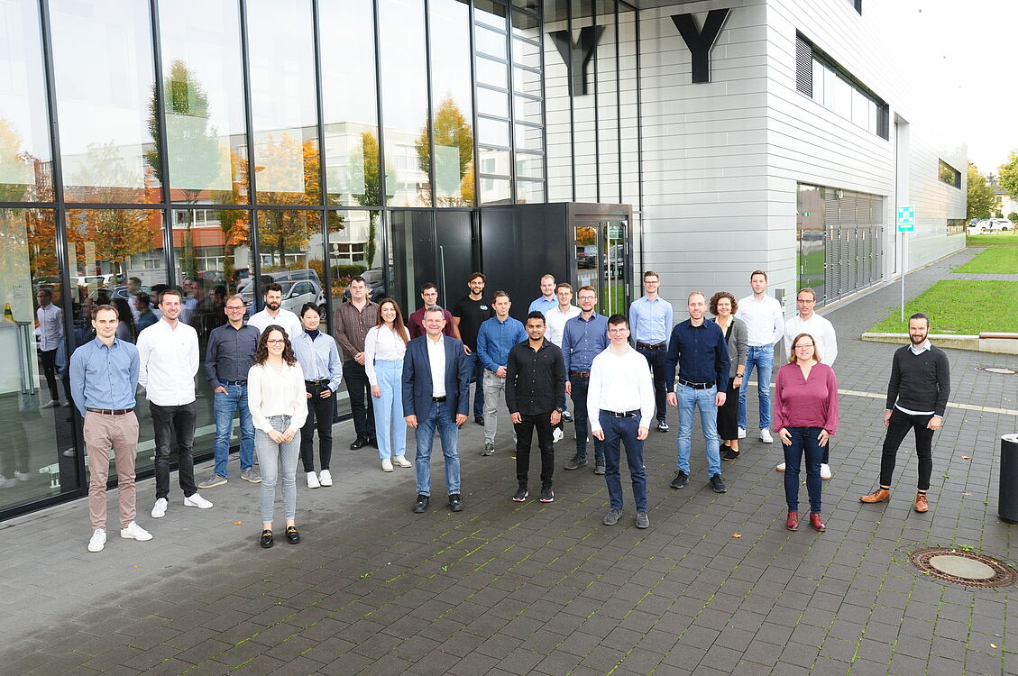 Mitarbeitende des Lehrstuhls für Leichtbau im Automobil stehen vor dem Y-Gebäude auf dem Campus der Uni Paderborn