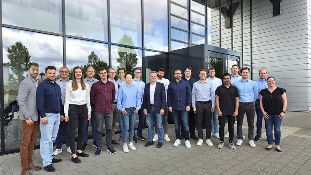 Mitarbeitende des Lehrstuhls für Leichtbau im Automobil stehen vor dem Y-Gebäude auf dem Campus der Uni Paderborn