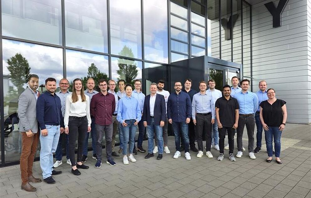 Mitarbeitende des Lehrstuhls für Leichtbau im Automobil stehen vor dem Y-Gebäude auf dem Campus der Uni Paderborn